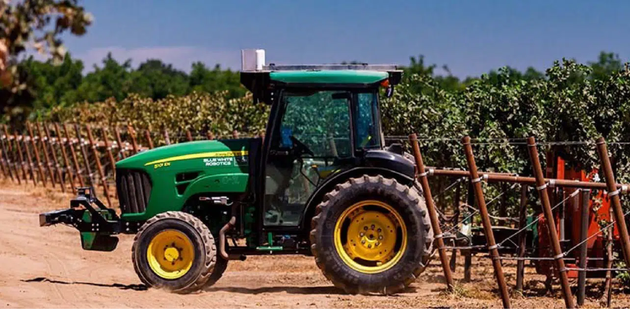 未舗装の道路を走る緑色のトラクター。